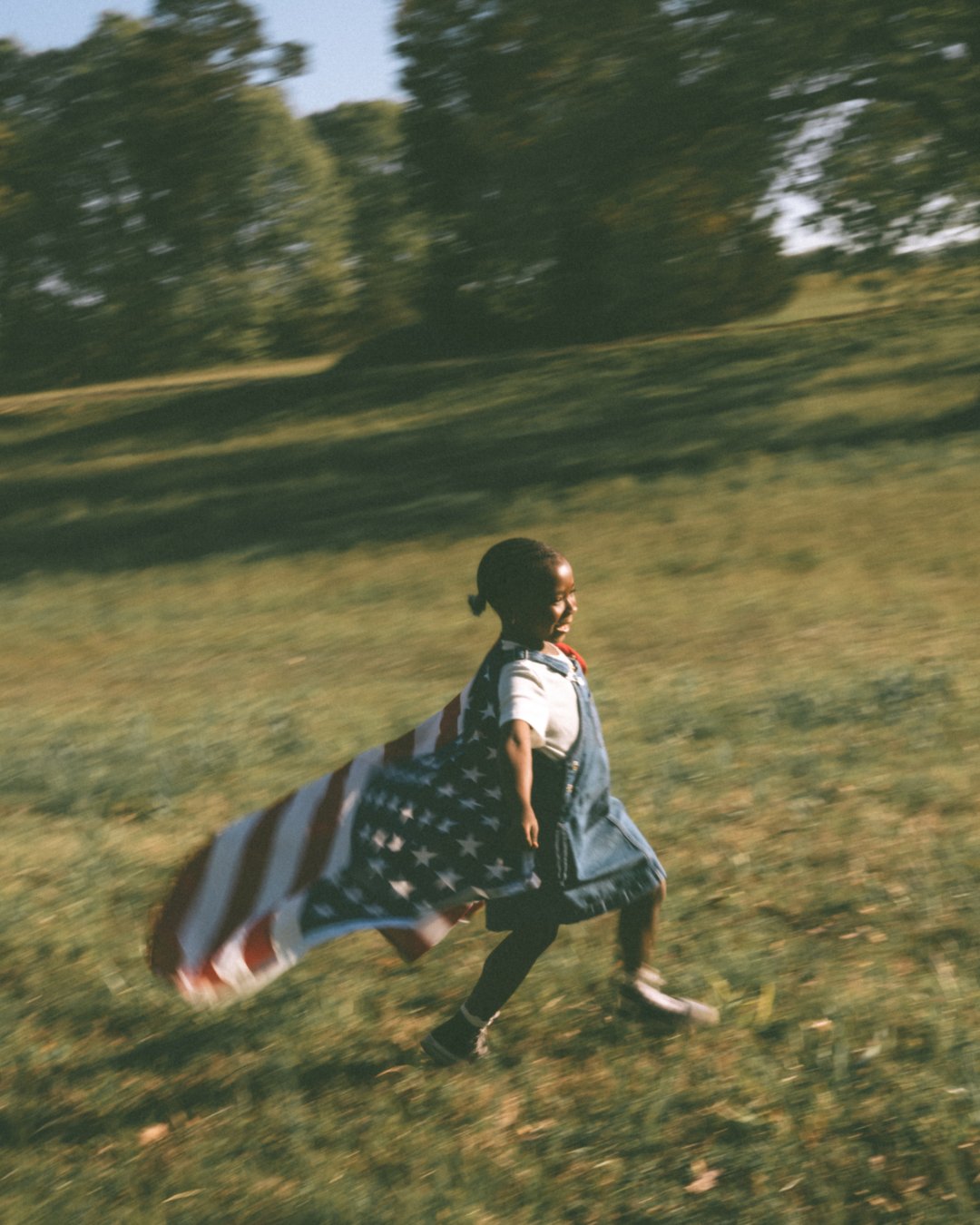 Girl running with a flag cape through the field